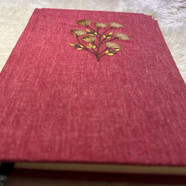Red notebook with an embroidered design on a textured surface